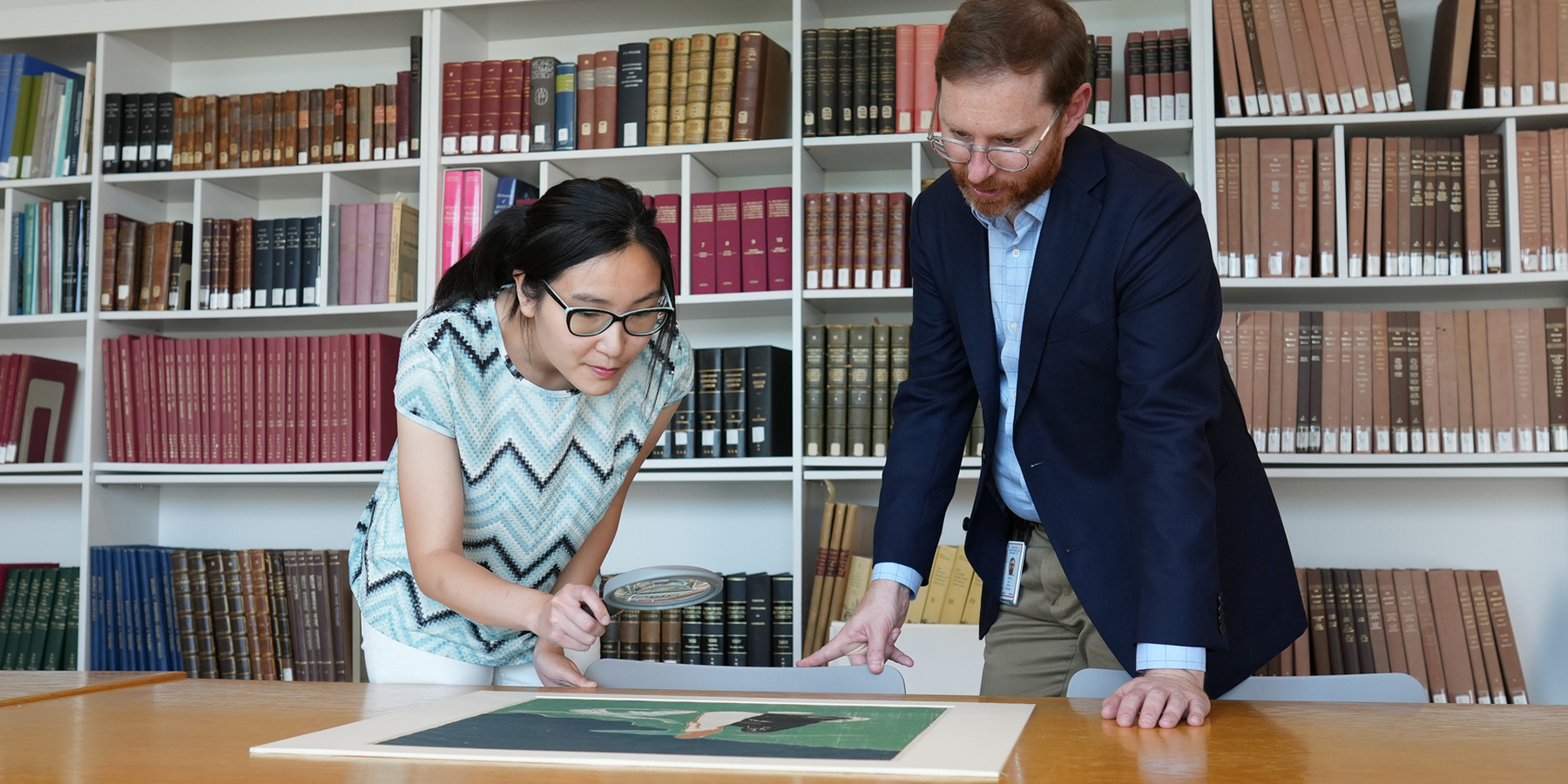 Staff and scholars view and discuss prints on display in the Study Center.