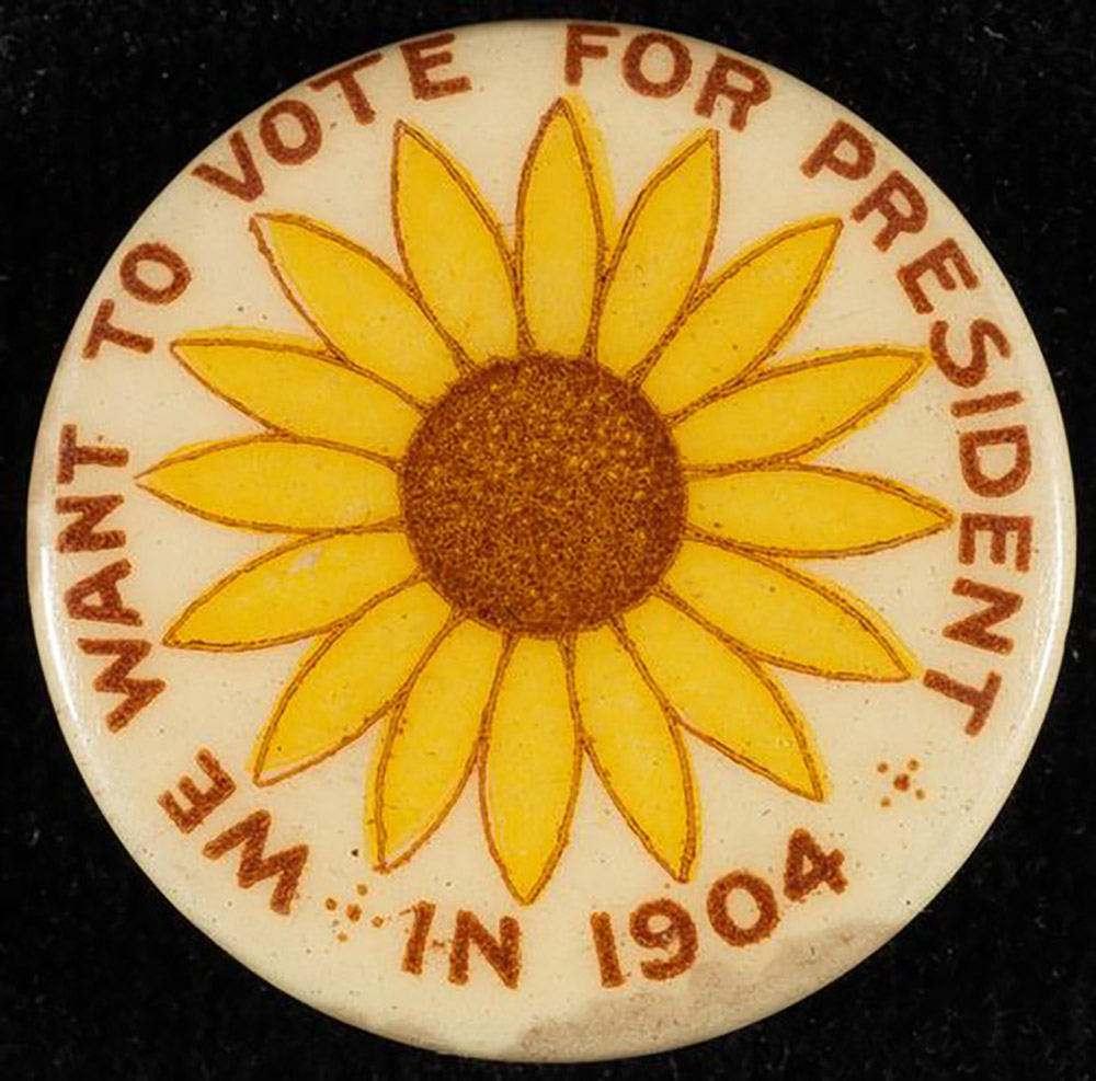 Circular-shaped button with sunflower in the middle and the words "We want to vote for president in 1904" going around the button