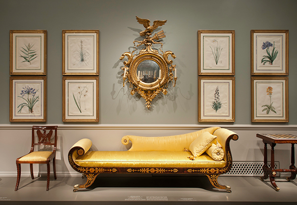Gold upholstered sofa surronded by chairs and a gilt mirror avove.