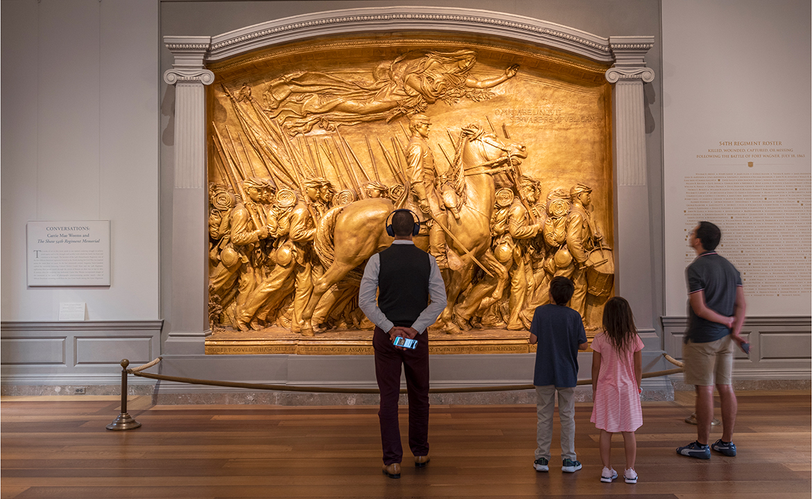 A visitor hears from Carl Cruz, descendant of a sergeant in the 54th Massachusetts Regiment, at the audio guide stop for Augustus Saint-Gaudens's "The Shaw 54th Regiment Memorial"