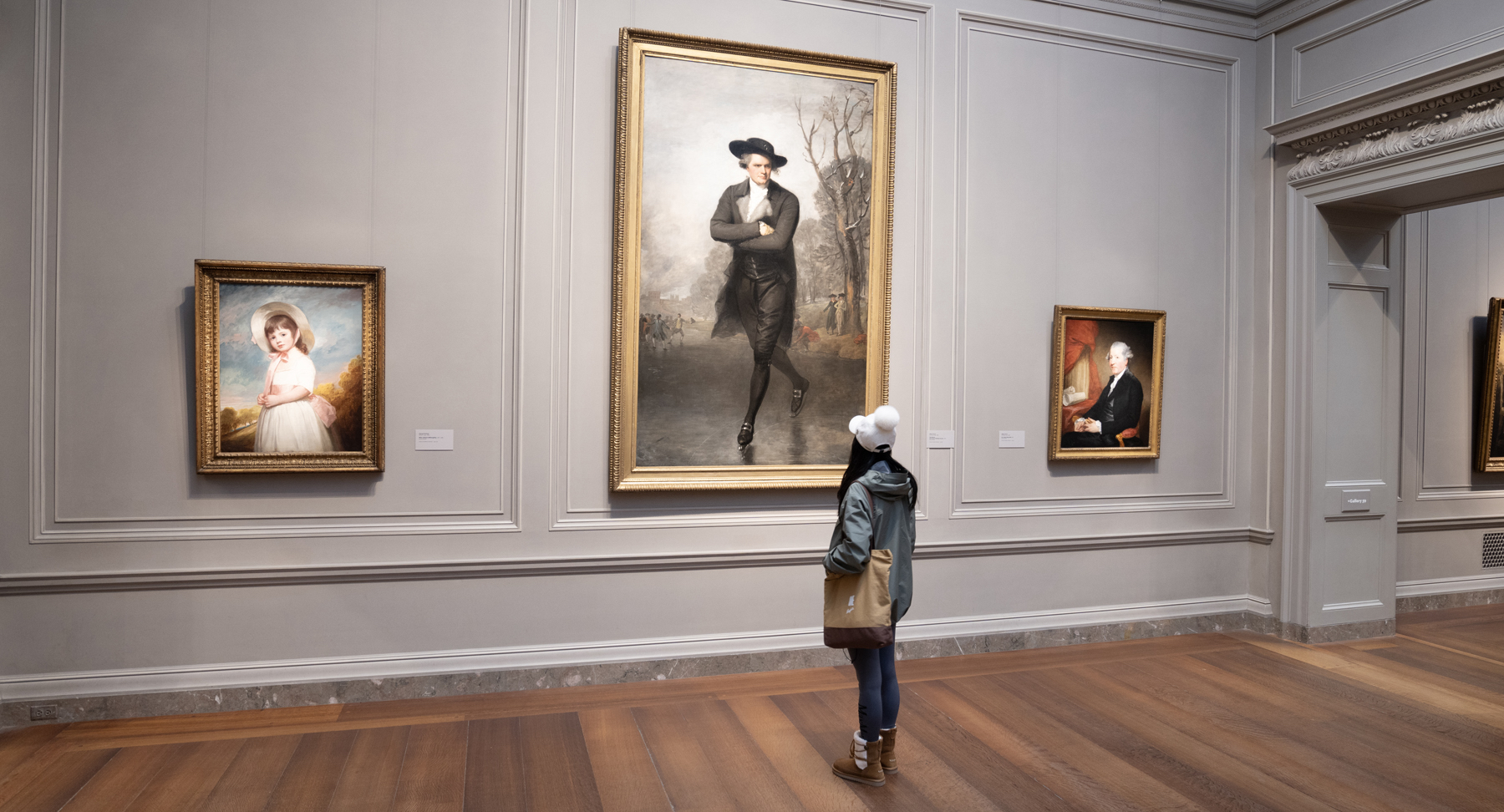 A museum visitor stands before Gilbert Stuart's The Skater
