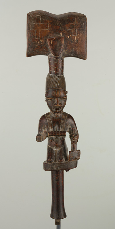 Carved wood figure resembling a torso on the bottom and an axe at top