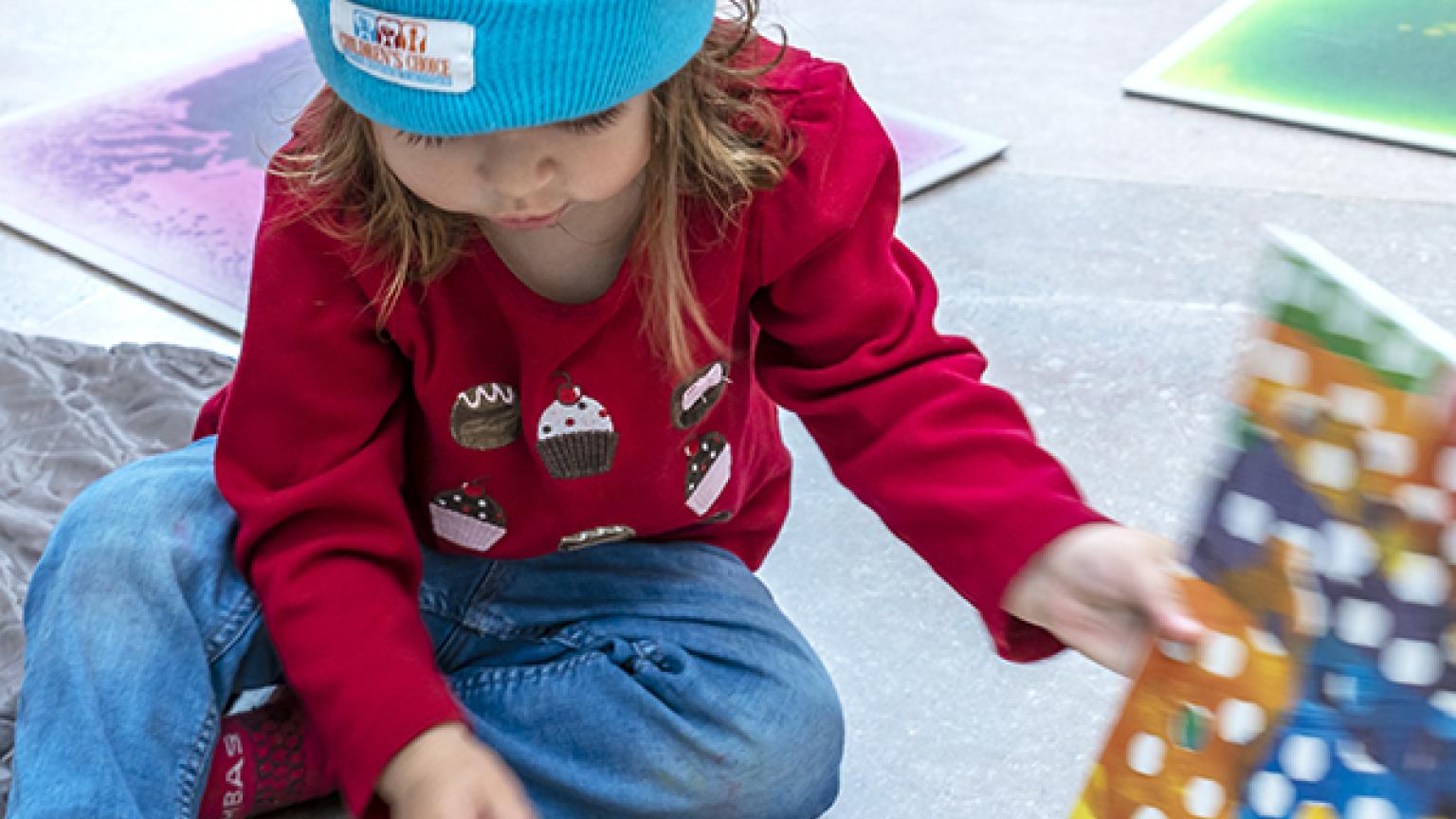 A very young visitor looking through a children's book in the National Gallery's East Building.