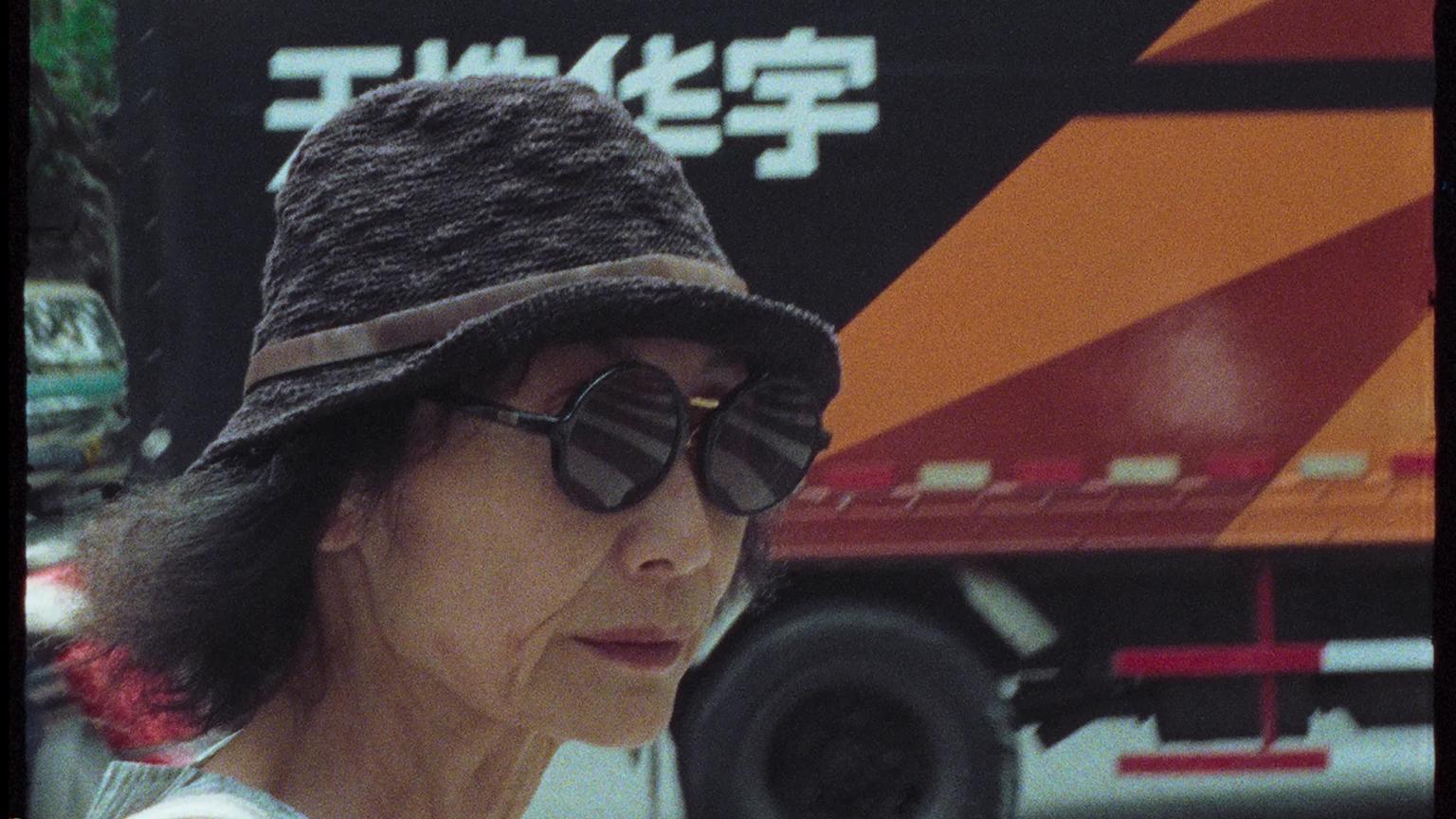 A woman wearing a hat with a circular brim and round sunglasses.