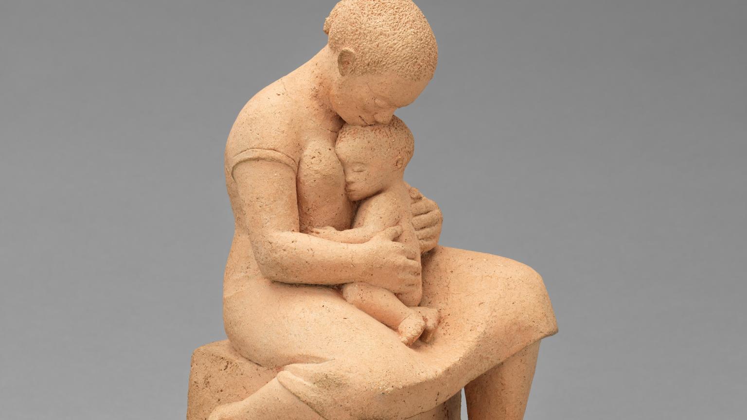 A sculpture of a woman holding a small child in her lap.
