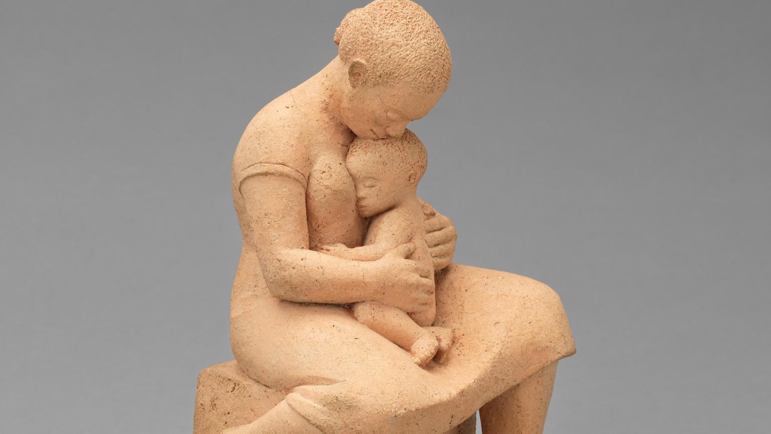 A sculpture of a woman holding a small child in her lap.