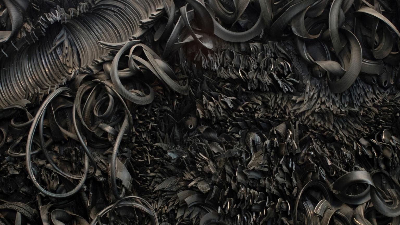 The wall-sized, horizontal sculpture consists of black rubber tires and tubing that has been sliced, stripped, woven, looped, twisted and otherwise manipulated into an expressive and abstract high-relief tableau.