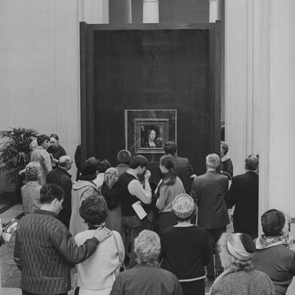 People gathered around looking at the Mona Lisa painting by Leonardo da Vinci