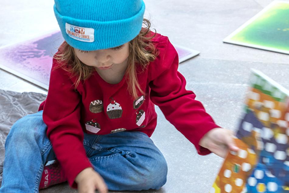 A very young visitor looking through a children's book in the National Gallery's East Building.