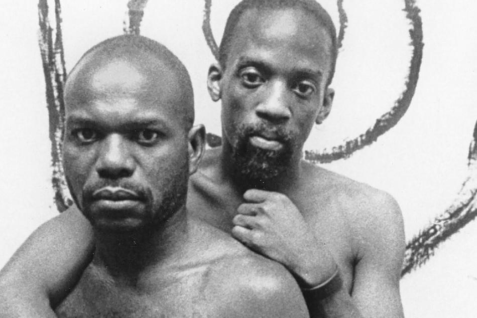 Two men without shirts on with very serious expressions on their faces.