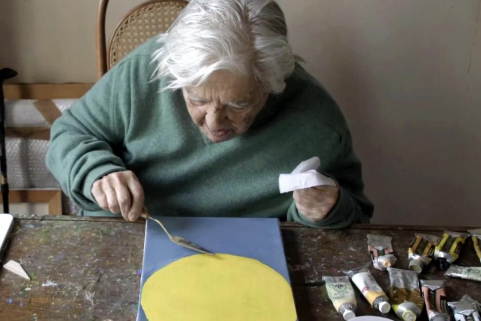 A woman sitting at a table working on an arts and crafts project.