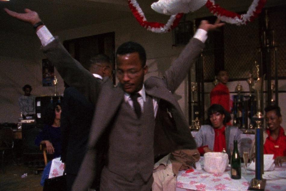 A man in a three-piece suit raising his arms.