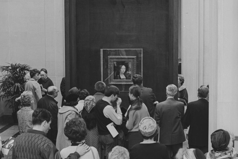People gathered around looking at the Mona Lisa painting by Leonardo da Vinci