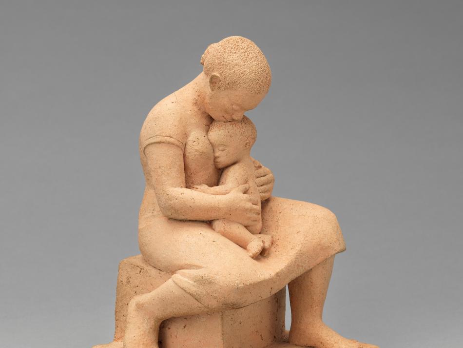 A sculpture of a woman holding a small child in her lap.