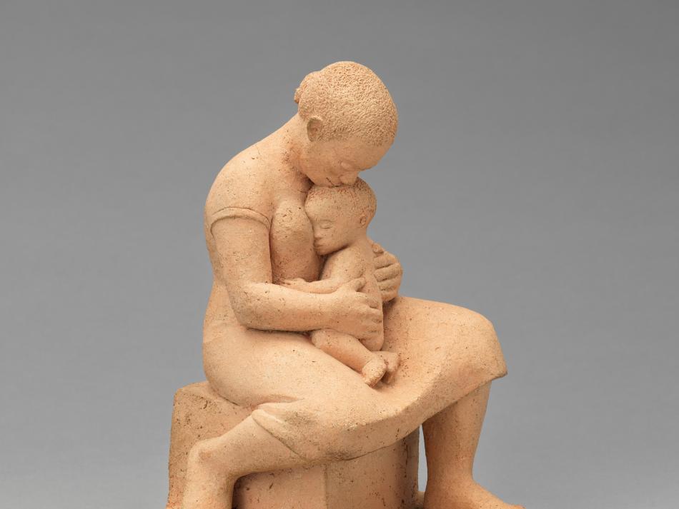 A sculpture of a woman holding a small child in her lap.