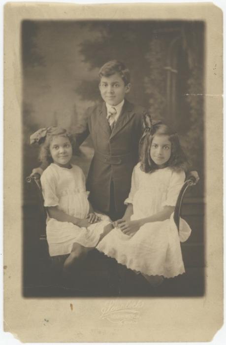 A photo of two little girls flanking a little boy. Elizabeth Catlett is the little girl on the left.