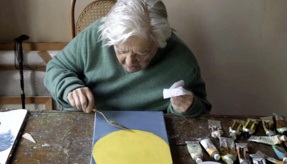 A woman sitting at a table working on an arts and crafts project.