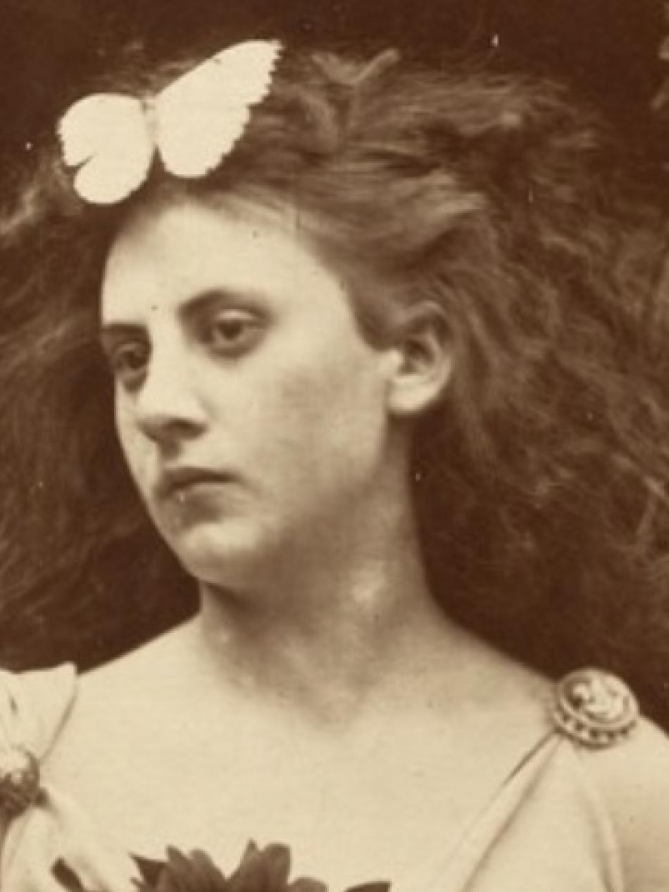 In this sepia toned image, a young woman with curly hair looks over her shoulder to our left.