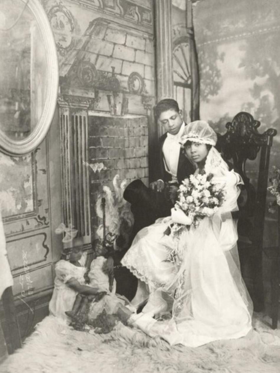 This is a black and white wedding photo of a young Black couple. The bride is holding roses.