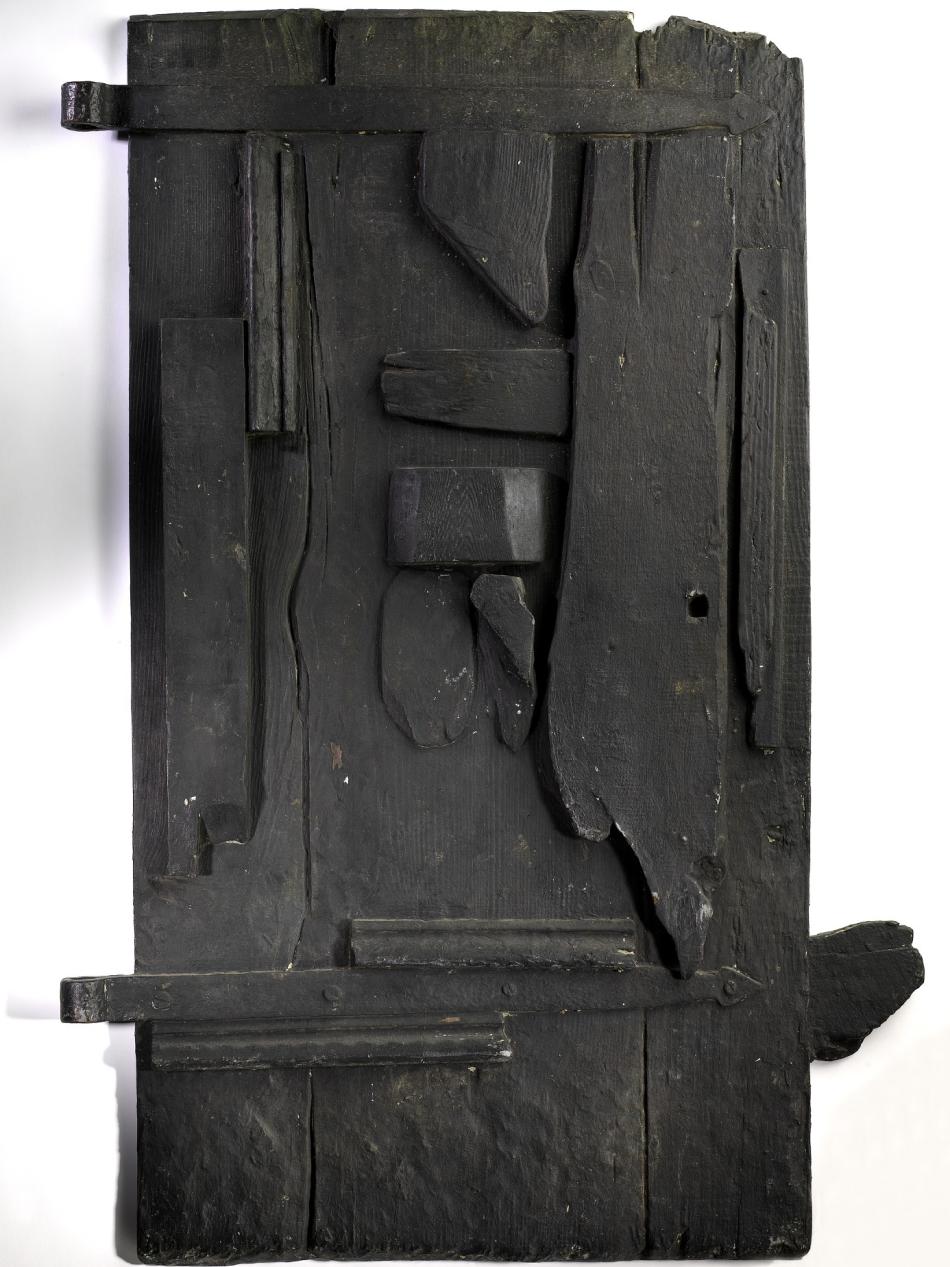 This black, freestanding, sculpture is taller than it is is wide and looks as though it's made of different components stuck together but on closer look, it seems to be carved out of one piece of wood.