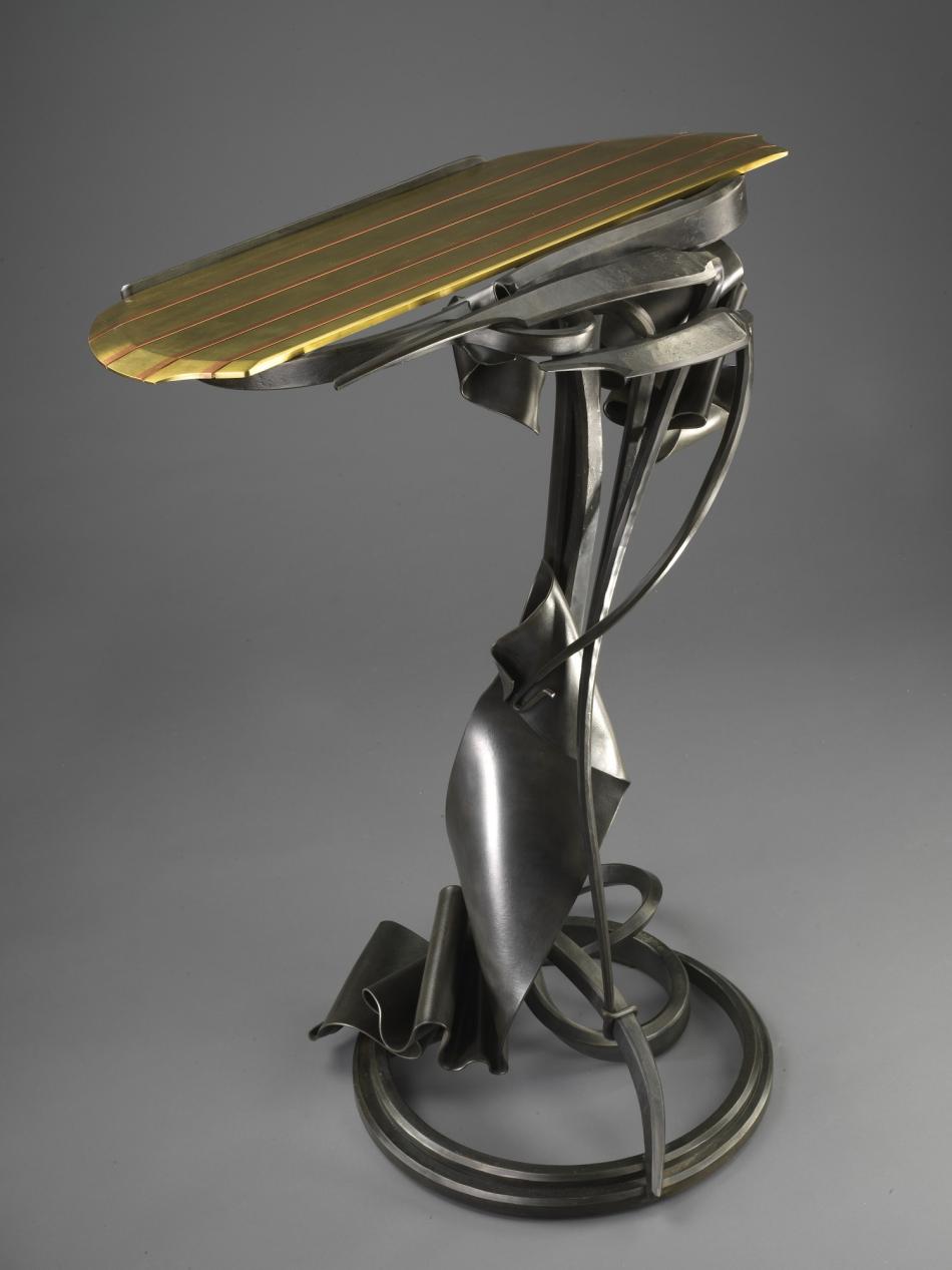 This medal pedestal or vase is black at it's base and gold slats make up the top surface.