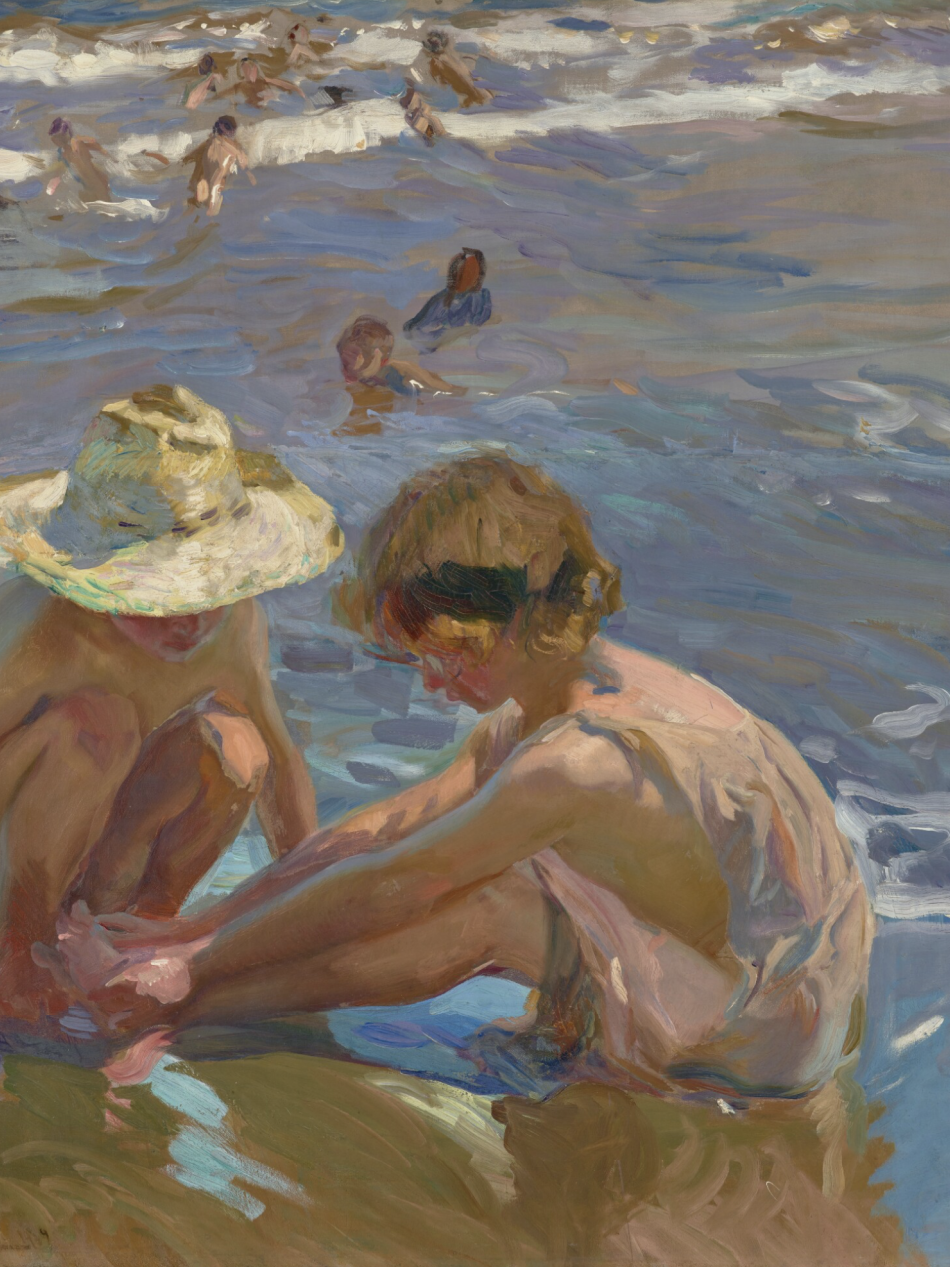 Two children play in the sand by the water.