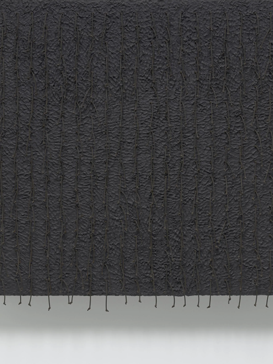 This black relief painting has a textured surface.